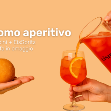 Mano che sorregge l'arancino, mano che versa lo spritz nel calice